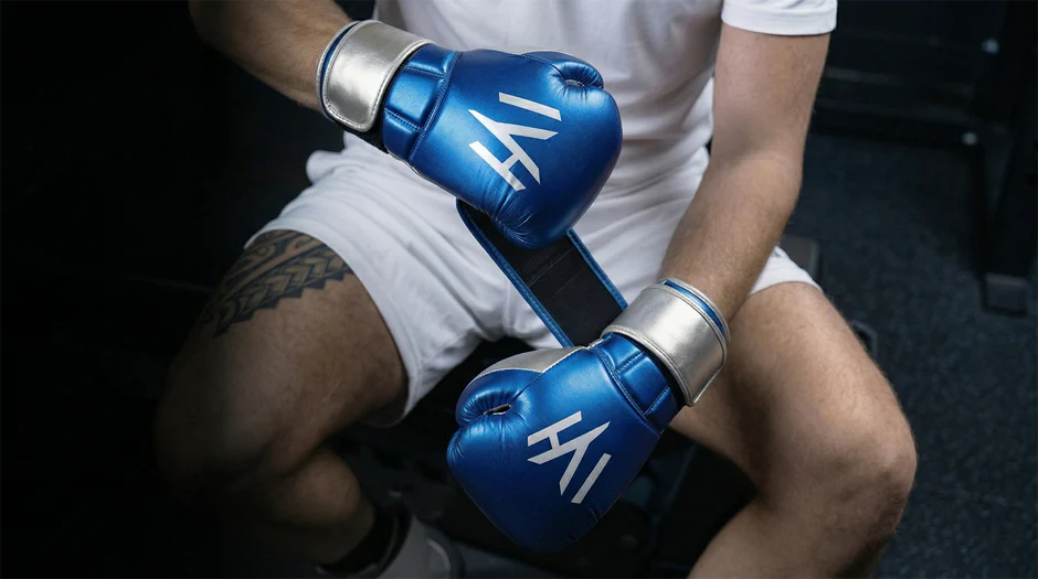 Athlete wearing MAYHM blue boxing gloves while wrapping hands before boxing, kickboxing, Muay Thai, and combat sports training.
